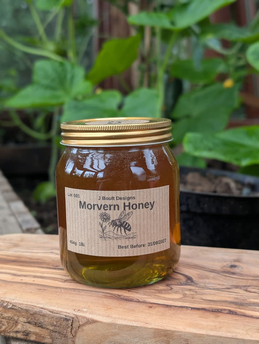 Jar of Morvern Honey on a wooden surface with plants in the background