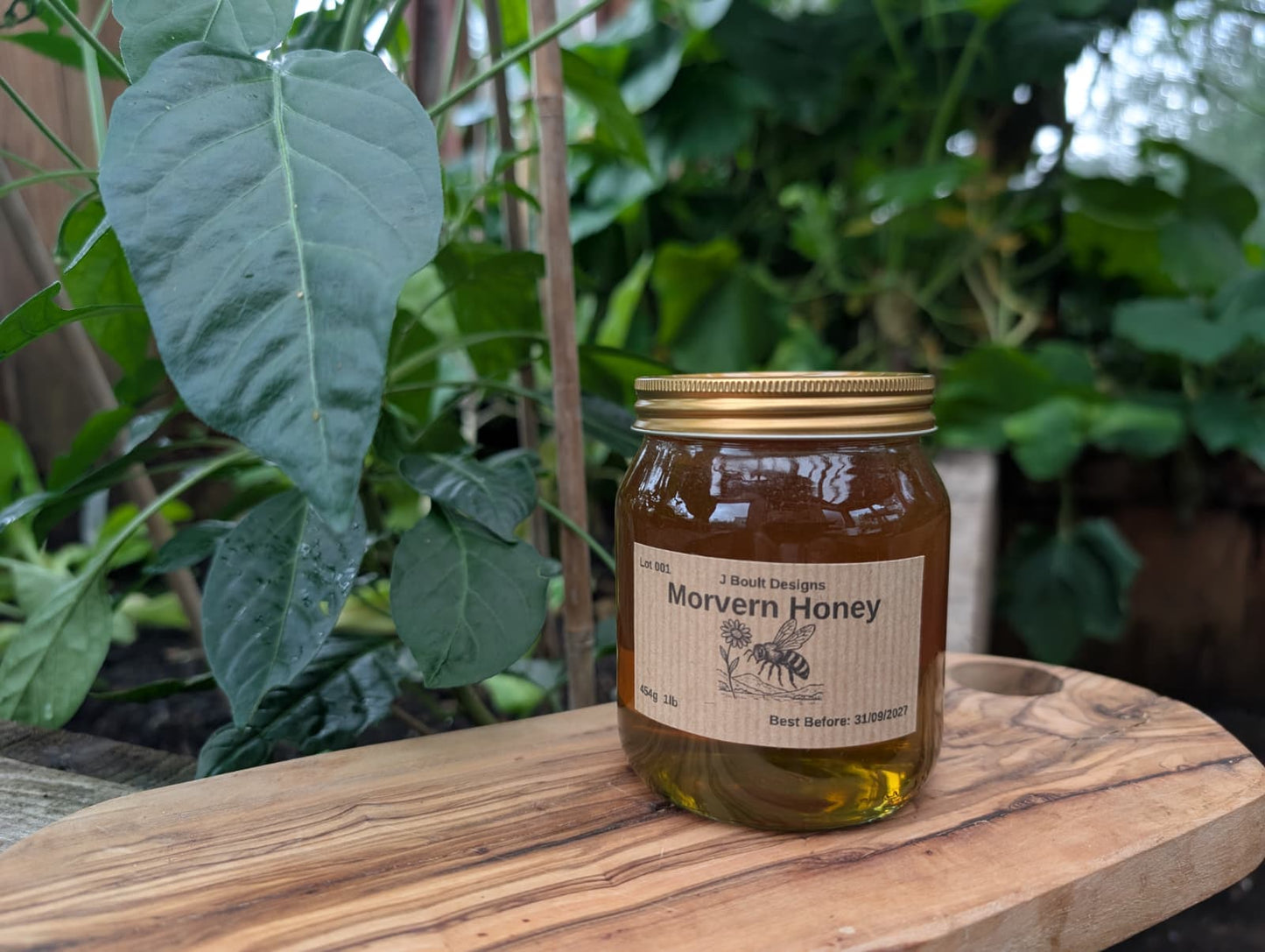 Jar of Morvern Honey on a wooden surface with green plants in the background